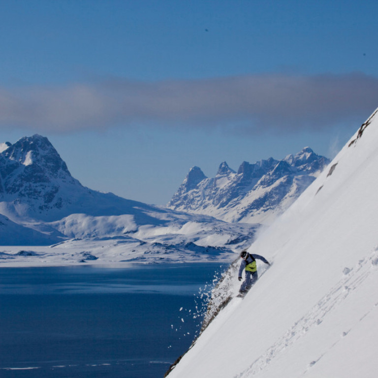 Heli Snowboarding on the east coast of Greenland from the top of the peak right down to the ice free waters of the fjord below where the helicopter awaits.