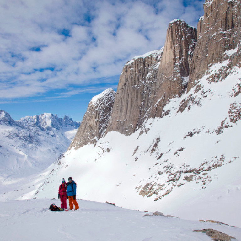 Waiting for the helicopter under the towering Granite peaks of the East Coast of Greenland after another fantastic heliskiing run in deep powder snow.