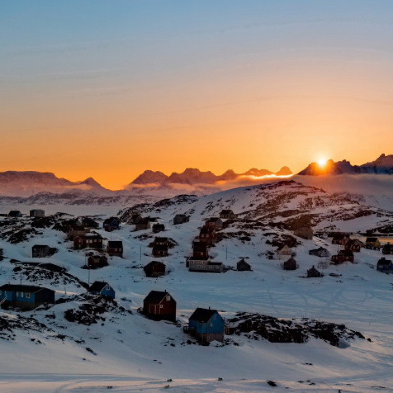 The sun sets over the hunting village of Kulusuk on the East Coast of Greenland. Kulusuk is our base of operations for our East Greenland Heli-skiing programs.  ©Eli Spiegel
