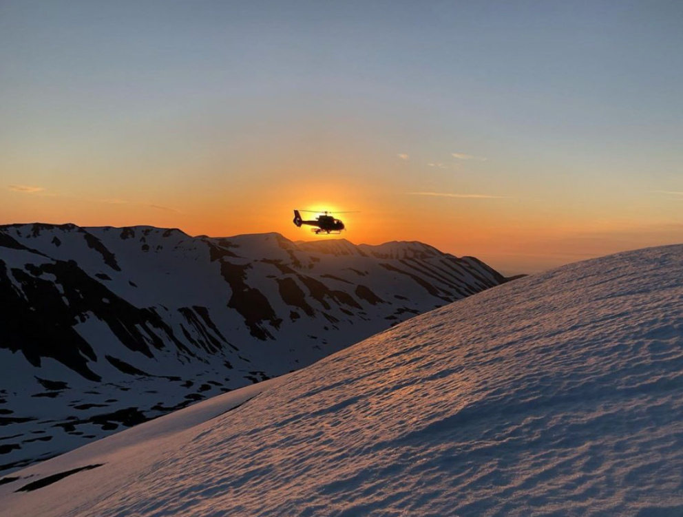 The helicopter flying off into the midnight sun after dropping off some skiers - June 2020